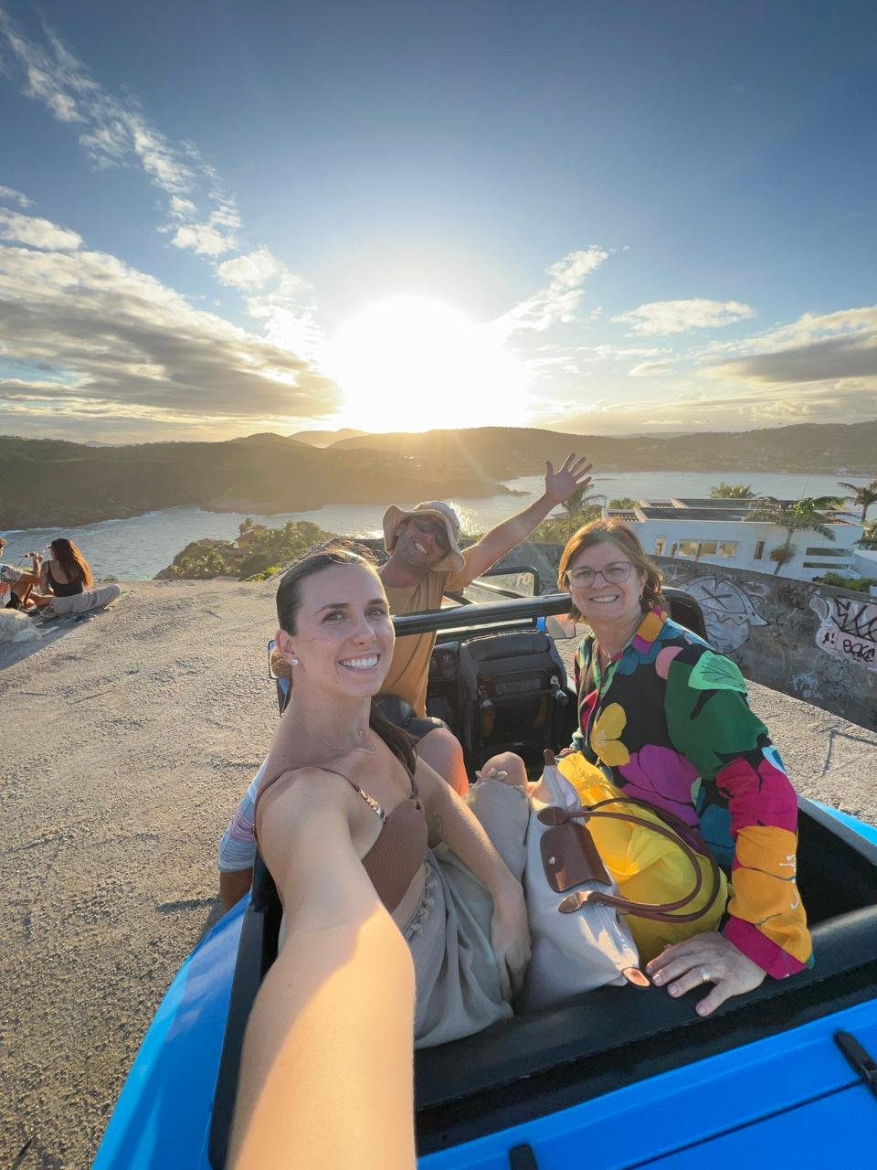 Pessoa em cima de um buggy azul durante o passeio de buggy em Búzios com a Búzios Trip Tour apreciando um belo por do sol