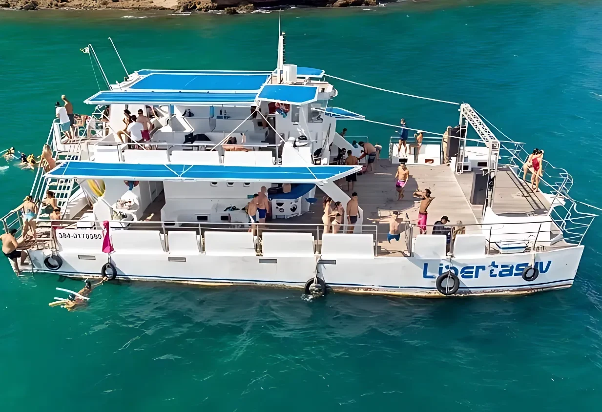 Passeio de catamarã em Búzios navegando pelo mar cristalino com turistas.
